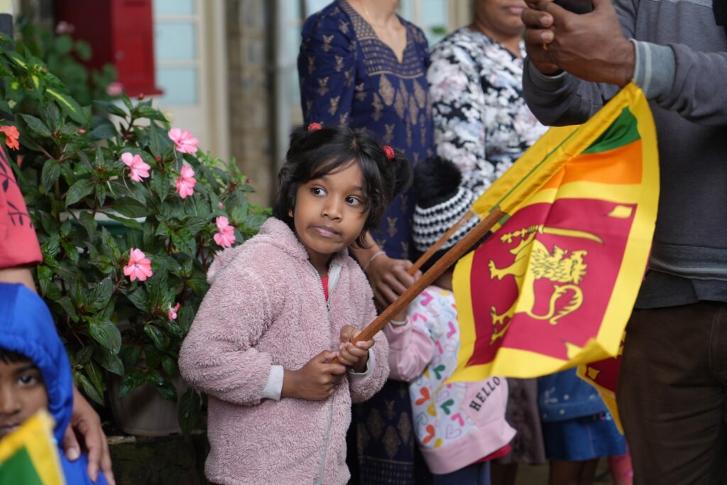 A little girl is waiting for the train holding a Sri Lankan flag